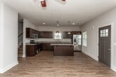 Located at 1805 Shiloh Rd NW in Kennesaw, Georgia, this two-story home offers a well-designed layout with consistent finishes throughout. The entry level features wood-style flooring that flows through the main living areas, beginning at a welcoming foyer with a dark-paneled front door and natural light from a large window. The spacious living area is outfitted with a ceiling fan and ample room for comfortable furnishings. The kitchen is a standout feature, showcasing rich dark cabinetry, light granite countertops, stainless steel appliances including a range, microwave, dishwasher, and refrigerator, plus a central island with pendant lighting — ideal for both cooking and entertaining. A convenient half bath with a pedestal sink is also located on the main floor. Upstairs, the bedrooms are carpeted and each equipped with ceiling fans and windows that bring in natural light. The bathrooms include full tub-shower combinations; one bathroom features dark cabinetry with granite counters matching the kitchen's aesthetic, while another offers a clean, all-white finish with wood-style flooring. The neutral color palette and modern finishes create a cohesive, move-in-ready environment throughout the home.