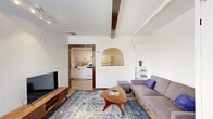 Located on N Warren Ave in Tucson, Arizona, this two-bedroom, one-bathroom home offers a thoughtfully designed single-floor layout that maximizes every square foot. The living room serves as the heart of the home, featuring distinctive exposed wood ceiling beams, light wood-style flooring, and a charming arched pass-through window that visually connects the space to the kitchen. Built-in shelving adds both function and character, while the front entry area provides ample closet storage.

The kitchen is efficiently laid out with white cabinetry, white appliances including a gas range and refrigerator, and a peninsula counter that opens toward the living area — ideal for casual dining or entertaining. Rich, dark wood door frames throughout create a striking contrast against the bright white walls.

The primary bedroom is a calm, minimal retreat with track lighting, light wood flooring, and a richly toned wood door frame. The second bedroom features a window with natural light, a wall-mounted mini-split system for climate control, and the same clean, neutral palette found throughout the home.

The bathroom is finished in crisp white tile with a pedestal sink, a tub and shower combination enclosed by bold black-framed glass sliding doors, and a recessed medicine cabinet — combining classic style with practical functionality.
