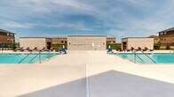 Located at 2290 SE Waco Pl in Waukee, Iowa, this outdoor amenity area serves as a central recreational hub for the surrounding residential community. The space is defined by two generously sized swimming pools with clear, blue water, each flanked by wide concrete sun decks equipped with wicker chaise lounge chairs ideal for relaxing under the open Iowa sky. The pool area is enclosed by a sleek, black wrought-iron fence with decorative stone pillar accents, providing both security and visual continuity with the surrounding multi-story residential buildings, which feature a combination of brick, stone, and board-and-batten siding. A dedicated clubhouse or amenity building adjoins the pool deck, offering direct access between indoor and outdoor spaces. Manicured green lawns and young ornamental plantings are visible beyond the fencing, contributing to a well-maintained and inviting atmosphere. A secure chemical storage room, constructed from matching light-colored masonry block and accessed via heavy steel double doors with appropriate hazard signage, is integrated into the facility's infrastructure. The overall design reflects a modern, community-oriented aesthetic that prioritizes outdoor recreation, safety, and attractive landscaping throughout the grounds.