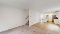 Located at 1043 Hinor Dr in Lebanon, Indiana, this two-story home offers five bedrooms and three full bathrooms across two well-proportioned floors. The main level features an open-concept living room and kitchen area, where light hardwood-style flooring creates a seamless, airy flow throughout the space. The kitchen is a standout highlight, equipped with stainless steel appliances including a range, microwave, and refrigerator, complemented by crisp white shaker cabinetry, a large island with an integrated sink, white quartz countertops, and recessed lighting overhead. The living room transitions naturally from the kitchen and features a sliding glass door that invites natural light and provides outdoor access. A staircase with a warm wood railing connects the main floor to the upper level. Upstairs, a carpeted hallway leads to five bedrooms, including a generously sized primary bedroom. The bedrooms are bright and neutrally finished, with windows that offer views of the surrounding greenery. All three bathrooms feature large-format tile flooring, white vanities, and tub-shower combinations. A utility room and closet round out the functional layout, making this home a practical and well-designed residence suitable for a variety of living arrangements.