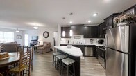 Located at 2300 Enterprise Place in Kingsport, Tennessee, this single-floor residence offers a thoughtfully designed layout with modern finishes throughout. An inviting entryway hallway leads into the heart of the home, providing a practical coat storage area before opening into the main living spaces.

The kitchen is a standout feature, showcasing dark espresso cabinetry that contrasts sharply with bright white countertops and a light wood-tone luxury vinyl plank floor. A central island with bar seating for multiple guests serves as both a prep area and a casual dining spot, illuminated by elegant pendant lights overhead. Stainless steel appliances, including a refrigerator, range, dishwasher, and microwave, complete the modern culinary space.

The kitchen flows seamlessly into the living room, which features a ceiling fan, large windows that allow generous natural light, and a welcoming, open ambiance ideal for relaxing or entertaining.

The bedroom offers plush carpeting, natural light through wide windows with blinds, and a ceiling fan, creating a restful and comfortable retreat.

The bathroom is clean and well-appointed, featuring a dark vanity with a light stone-style countertop, a large mirror, and a shower-tub combination, all tied together with consistent neutral tones. The cohesive design and quality finishes make this a polished and functional living space.