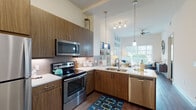 Located at 626 NE Second Ave in Fort Lauderdale, Florida, this single-floor residence offers a thoughtfully designed open layout that blends modern finishes with functional living. The kitchen is a standout feature, equipped with a full suite of stainless steel appliances including a refrigerator, electric range, built-in microwave, and dishwasher. Rich wood-tone cabinetry extends to the ceiling for generous storage, while white quartz countertops and a geometric-patterned tile backsplash add contemporary style. Pendant lighting over the sink and a track light fixture illuminate the space, which flows seamlessly into the living area. The living room is bright and inviting, benefiting from large sliding glass doors that flood the space with natural light and provide views of the landscaped outdoor area. A ceiling fan adds comfort to this well-lit gathering space. The bedroom is a calm retreat featuring plush carpeting, a window with outdoor views, and warm neutral tones. The full bathroom is finished with clean subway tile surrounding the soaking tub and shower, wood-tone vanity cabinetry, and white countertops. Throughout, wood-look flooring ties the main living areas together for a cohesive and modern aesthetic.