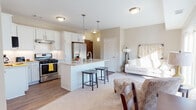 This single-story residence in Livonia, Michigan, offers a thoughtfully designed open-concept layout that maximizes functionality and comfort. The neutral color palette of warm beige and white tones flows consistently throughout, creating a cohesive and welcoming atmosphere.

The kitchen serves as the centerpiece of the main living area, featuring white shaker-style cabinetry, granite countertops, and a subway tile backsplash. Stainless steel appliances include a gas range, refrigerator with ice maker, built-in microwave, and dishwasher. A central island with pendant lighting overhead provides seating for two and doubles as additional prep space. Durable wood-look flooring anchors the kitchen and transitions seamlessly into the adjacent living area, which is finished with plush carpet. A dedicated laundry closet with a stacked washer and dryer is conveniently located off the kitchen.

The bedroom is generously sized with soft carpeting, vaulted ceiling details, and a bay-style window arrangement that invites abundant natural light and outdoor views. The full bathroom is finished with granite countertops, white cabinetry, wood-look flooring, and a tub-shower combination with sliding glass doors.