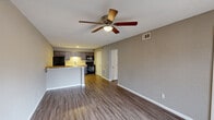 Located at 54 Arbor Village Ct in Ferguson, MO, this 2-bedroom, 1-bathroom unit offers a practical and well-designed single-floor layout. The open-concept living and kitchen area serves as the heart of the home, featuring durable hardwood-style flooring, neutral gray walls, and a textured ceiling with a ceiling fan overhead. The kitchen is equipped with dark cabinetry, black appliances including a refrigerator, microwave, and range, and a warm wood-toned breakfast bar countertop that separates the space from the living area. A sliding glass door in the living space allows natural light to fill the room and provides direct outdoor access. The two bedrooms continue the consistent flooring and neutral color palette, each outfitted with a ceiling fan and closet access. The primary bedroom benefits from two windows dressed with roller shades, bringing in ample natural light. A connecting hallway links the bedrooms to the full bathroom, which features a dark wood vanity with a white countertop, a mirror, tub-shower combination, and wood-look tile flooring. Throughout the unit, clean white trim and doors create a crisp, cohesive aesthetic that complements the overall neutral tone of the space.