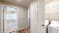 This three-bedroom, two-bathroom single-story home in Fayetteville, Arkansas offers a practical and well-appointed layout with clean, modern finishes throughout. The open kitchen and living area serves as the heart of the home, featuring rich dark wood cabinetry, granite-look countertops, a full suite of stainless steel appliances including a refrigerator, range, and built-in microwave, and warm wood-look vinyl flooring. Recessed lighting adds a polished touch overhead. The living area is bathed in natural light from a large window and opens to the outdoors through French doors, complemented by a ceiling fan for year-round comfort. A central hallway connects the three bedrooms, two of which feature plush carpeting and ceiling fans, while the primary bedroom offers wood-look flooring and generous proportions. The dedicated closet provides additional storage. Both bathrooms are consistently finished with dark wood vanities, white countertops, wood-look flooring, and shower-tub combinations with sliding glass enclosures. Neutral warm-beige walls and crisp white trim carry throughout, creating a cohesive and inviting atmosphere across every room.