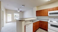 Located at 15059 Caseta Dr in Houston, TX, this single-story, one-bedroom, one-bathroom unit offers a practical and well-organized layout. The kitchen is a standout feature, showcasing rich warm-toned wood cabinetry, granite-style countertops, and a full suite of white appliances including a refrigerator, electric range, built-in microwave, and dishwasher. A peninsula breakfast bar seamlessly connects the kitchen to the living area, creating an open, functional flow. The living room is finished with plush carpet and receives natural light through a window overlooking the exterior. Hardwood-style flooring runs through the kitchen and hallway areas, providing a clean contrast to the carpeted spaces. The bedroom is a comfortable size, featuring carpet flooring, a ceiling fan, a window with neighborhood views, and access to two closets for ample storage. The bathroom includes a vanity with matching wood cabinetry, granite-style countertops, a mirror, and a tiled shower with a grab bar. A dedicated laundry area adds everyday convenience. Neutral wall tones and clean finishes throughout give the space a bright and move-in-ready feel.