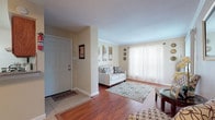 This single-floor 1-bedroom, 1-bathroom residence offers a thoughtfully designed layout that maximizes comfort and functionality. The entry foyer transitions seamlessly into the living area, which features warm hardwood flooring, crown molding, and large windows dressed with sheer curtains that allow abundant natural light to fill the room. A sliding glass door opens to a private patio, extending the living space outdoors.

The galley-style kitchen is efficiently organized with rich oak cabinetry, granite-look countertops, tile backsplash, and white appliances including a range and refrigerator. A pass-through counter connects the kitchen to the adjacent dining area, which features tile flooring and a ceiling fan, making it ideal for everyday meals or entertaining.

The bedroom is a peaceful retreat with plush carpet, a ceiling fan, and a sliding glass door that provides additional outdoor access and natural light. Vertical blinds offer privacy when desired. The full bathroom includes an oak vanity with a granite-look countertop, tile flooring, and ample storage. Throughout the residence, neutral tones and consistent finishes create a cohesive and welcoming ambiance.