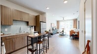 This thoughtfully designed one-bedroom, one-bathroom residence in Round Rock, Texas offers a functional and stylish open-concept layout across a single floor. Light wood-style flooring flows throughout the main living areas, connecting the kitchen and living room seamlessly.

The kitchen is equipped with warm wood-toned cabinetry, a light blue tile backsplash, granite countertops, and stainless steel appliances, including a full-size refrigerator. A built-in island with bar seating provides additional prep and dining space, making the kitchen both practical and inviting.

The living room is bright and airy, bathed in natural light from large sliding glass doors that open to an outdoor area. A ceiling fan overhead adds comfort, while the open layout provides flexible space for lounging and dining.

The bedroom features plush carpet flooring, a bold accent wall, and a ceiling fan. A large window allows natural light to fill the room, creating a comfortable retreat.

The bathroom offers a clean, elongated layout with wood-toned vanity cabinetry, granite countertops, built-in open shelving, wood-style flooring, and a tiled tub-shower combination. A hallway connects the main rooms, completing this efficient and well-appointed residence.