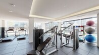 Located at 214 W Erie St in Chicago's vibrant River North neighborhood, this well-appointed fitness center offers a comprehensive workout environment across a single floor. The space is designed with a clean, contemporary aesthetic, featuring recessed tray ceilings with warm ambient lighting, durable rubber flooring, and expansive floor-to-ceiling windows that flood the interior with natural light and frame views of the surrounding Chicago skyline.

The facility is equipped with a full suite of Life Fitness branded equipment, including multiple treadmills and elliptical machines positioned along the windowed perimeter to maximize the city views during cardio sessions. The strength training area features a robust selection of cable and resistance machines, a comprehensive dumbbell rack, adjustable benches, and a functional training rig. A dedicated accessory zone includes medicine balls and stability balls on organized racks, catering to a range of training styles.

A hydration station with a filtered water dispenser is conveniently integrated into the cardio area. Large mirrors are strategically placed throughout the space to enhance the sense of openness. The facility is accessible via glass-paneled doors and includes open shelving near the entry. The overall ambiance is bright, modern, and professional, offering an inviting environment for a focused and effective workout experience.