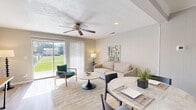 This two-story home offers a practical and comfortable layout across two floors. The ground floor hosts the main living areas, including a bright living room featuring wood-look flooring, a ceiling fan, and a large sliding glass door that floods the space with natural light and provides outdoor views. The adjacent kitchen is equipped with white cabinetry, light countertops, a black electric range, and an over-the-range hood, with a convenient pass-through opening to the living and dining area. The upper floor is home to both bedrooms and bathrooms. The generously sized primary bedroom features soft carpet flooring, built-in closets, and access to a full bathroom complete with an extended vanity, white cabinetry, tiled walls, and wood-look flooring. The second bedroom is well-proportioned with carpet flooring, multiple windows that bring in natural light, and ample closet storage with louvered bi-fold doors. A secondary bathroom serves this floor as well, featuring a compact vanity and a window for natural ventilation. Throughout the home, neutral tones, clean finishes, and thoughtful storage solutions contribute to a cohesive and functional living environment.