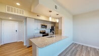 Located at 5222 Shadydell Dr in Fort Worth, TX, this single-floor, one-bedroom, one-bathroom home offers a well-designed layout that maximizes every square foot. The open-concept living, dining, and kitchen area serves as the heart of the home, featuring vaulted ceilings, warm light wood-style flooring, and abundant natural light from multiple windows with blinds. The kitchen is appointed with sleek gray cabinetry extending to the ceiling, granite countertops, stainless steel appliances including a refrigerator, range, and microwave, and a large peninsula island with a sink — ideal for both cooking and casual dining. Pendant lighting above the island adds a modern touch. The living area includes a door leading directly to a private balcony, bringing in outdoor views and additional light. The carpeted bedroom is generously sized with a ceiling fan, a large window overlooking the outdoors, and a closet with bi-fold doors. The bathroom features granite countertops, gray cabinetry, and direct access to a dedicated closet. An additional flexible room serves as a home office, also finished with light wood-style flooring and a ceiling fan. A dedicated in-unit laundry room with side-by-side washer and dryer and built-in shelving rounds out this thoughtfully appointed home.