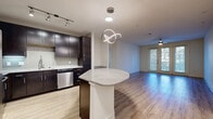 Located at 6215 Via la Cantera in San Antonio, Texas, this well-appointed 2-bedroom, 3-bathroom single-floor residence offers a thoughtfully designed layout that balances comfort and modern style. The open-concept kitchen is a standout feature, showcasing rich dark espresso cabinetry, granite countertops, a mosaic tile backsplash, stainless steel appliances including a dishwasher, and a center island topped with granite and accented by a striking sculptural pendant light. The kitchen flows seamlessly into the living area, which features warm wood-look flooring, a ceiling fan, and a glass door that fills the space with natural light and provides outdoor access. Both bedrooms are carpeted and generously sized, each offering ceiling fans and windows with lush outdoor views. The primary bedroom connects to an en-suite bath featuring tile flooring, granite-topped dark cabinetry, and a tub-shower combination. Four closets throughout the home provide ample storage, including walk-in closets with built-in shelving. A dedicated laundry room accommodates a full-size washer and dryer. With three full bathrooms, four closets, and a hallway connecting the living spaces, this residence offers practical functionality alongside contemporary finishes throughout.