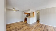 This well-appointed 1-bedroom, 1-bathroom residence offers a functional and comfortable single-floor layout. The living room serves as the heart of the home, featuring warm hardwood-style flooring, a ceiling fan, and a classic tiled fireplace with a white mantel — a standout architectural detail that adds character to the space. Vertical blinds along a sliding door allow for natural light control and access to the outdoors.

The kitchen is semi-open to the living area via a peninsula breakfast bar, and is equipped with warm wood cabinetry, light countertops, stainless steel appliances — including a refrigerator, microwave, and range — and recessed lighting overhead. The galley-style layout provides ample counter space on both sides, making it practical for everyday cooking.

The bedroom is a comfortable, carpeted retreat featuring a window with exterior views and a dedicated closet for storage. The neutral tones and soft carpet create a calm and restful environment.

The bathroom is clean and functional, featuring a full tub-shower combination with white tile surround, chrome fixtures, and wood-style flooring. Throughout the unit, neutral wall tones and consistent flooring choices create a cohesive, move-in-ready aesthetic.