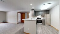 Located at 806 Riverwalk Dr in Waukesha, Wisconsin, this well-appointed one-bedroom, one-bathroom unit offers a functional and comfortable single-floor layout. The open-concept kitchen flows seamlessly into the combined dining and living area, creating an inviting and versatile space. The kitchen is outfitted with dark gray cabinetry, a marble-look countertop peninsula with a built-in sink, stainless steel appliances including a gas range and refrigerator, and durable light wood-tone vinyl flooring. A skylight and recessed lighting keep the area bright and welcoming. The living room is carpeted and features a sliding glass door that opens to a private balcony, filling the space with natural light and outdoor views. The generously sized bedroom is carpeted as well, with a window for additional natural light and warm wood-trimmed doors. It includes access to a dedicated walk-in closet outfitted with wire shelving and organizers, plus a secondary closet nearby. The bathroom is clean and modern, featuring a tub-shower combo, a dark-vanity with a white countertop, and wood-tone vinyl flooring consistent with the rest of the unit. A utility area with an electrical panel and additional storage access completes this well-organized home.