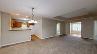 Located at Hampton Knoll Drive in Akron, Ohio, this single-floor, three-bedroom, two-bathroom residence offers a practical and comfortable layout across a well-utilized footprint. The kitchen is outfitted with warm honey-toned wood cabinetry, light countertops, a double-basin sink, and white appliances including a dishwasher and range, all set on easy-to-maintain hardwood-style flooring. The living area features vaulted ceiling detail, plush carpeting, and access to multiple rooms via a connecting hallway, creating an open and navigable flow throughout the home. Each of the three bedrooms is carpeted for comfort, with neutral warm-toned walls and ample natural light — one bedroom notably features a large window with a pleasant tree-lined view. The primary bedroom is generously sized and includes direct access to a private bathroom equipped with a single-sink vanity featuring wood cabinetry and light countertops, hardwood-style flooring, and a walk-in closet with wire shelving. A second full bathroom includes a tub-shower combination with chrome fixtures. Additional storage is provided through two closets fitted with wire rack shelving systems. The consistent neutral color palette and clean finishes throughout lend the space a cohesive, move-in-ready character.