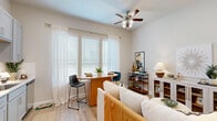 Located in Conroe, TX, this well-appointed one-bedroom, one-bathroom residence offers a smart, efficient layout across a single floor. The open-concept kitchen is a standout feature, showcasing quartz countertops with subtle veining, gray shaker-style cabinetry, a white subway tile backsplash, stainless steel appliances including a French door refrigerator and dishwasher, and a peninsula with a stainless undermount sink — ideal for both cooking and casual dining. The kitchen flows naturally into the living area, which is brightened by a ceiling fan and windows overlooking the community grounds. Light wood-look flooring runs throughout the main living spaces, lending warmth and continuity. The bedroom offers a comfortable footprint, natural light through a window with blinds, and direct access to a generously sized walk-in closet equipped with dual hanging rods and built-in shelving. The full bathroom features gray vanity cabinetry with a white countertop, a tub-shower combination, and wood-look flooring. A dedicated laundry area adds everyday convenience. The covered patio, framed by black metal railings and cheerful exterior siding, provides a pleasant outdoor retreat with views of the landscaped community, complete with palm trees and well-maintained green spaces.