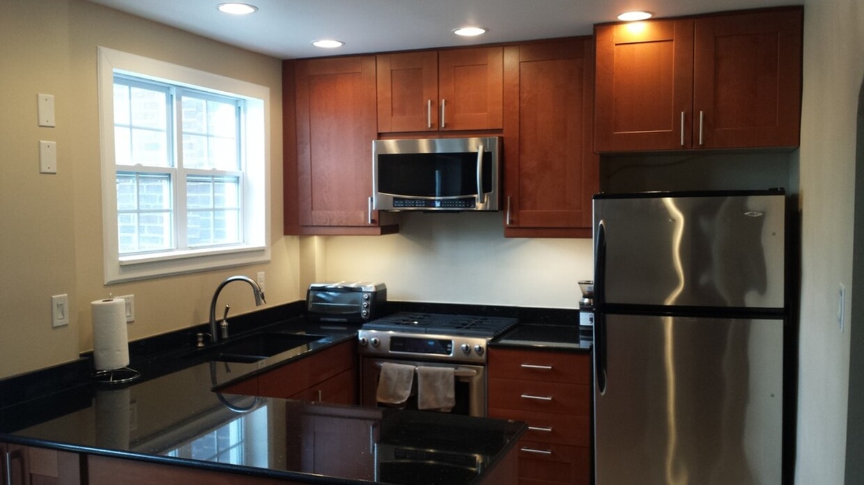 Renovated kitchen with new cabinetry, granite countertops, and oversized stainless steel refrigerator, gas range, dishwasher, and garbage disposal - 519 N Payne St