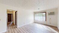 Located at 516 N Fourth St in Coleman, Michigan, this two-bedroom, one-bathroom unit offers a straightforward and functional single-floor layout. The living room welcomes natural light through a large window fitted with vertical blinds, and features light wood-style laminate flooring that extends into the kitchen and hallway areas, lending a clean, cohesive look throughout the common spaces. A wall-mounted air conditioning unit provides climate control in the living area. The kitchen is designed in a U-shaped configuration, maximizing counter and storage space with warm oak cabinetry, white countertops, and a double stainless steel sink—offering an efficient and organized workspace. Both bedrooms are carpeted in a neutral tan tone, providing a comfortable underfoot feel. Each bedroom benefits from natural light via windows with horizontal blinds, and the primary bedroom offers a notably spacious footprint. A connecting hallway leads to the full bathroom, which features a wood-toned vanity with an integrated sink, a lighted mirror, and a full shower-tub combo, all set on wood-style vinyl flooring. A dedicated closet adds practical storage to complete the layout.