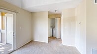 Located in Bradenton, FL, this two-bedroom, one-bathroom unit offers a practical and comfortable single-floor layout. The kitchen is well-appointed with white cabinetry, stainless steel appliances including a range and refrigerator, a double sink, and warm hardwood-style flooring that adds a clean, inviting feel. The adjoining living area is finished with neutral carpet and textured ceilings, creating a cohesive and easy-to-maintain space. Both bedrooms are carpeted and feature warm beige tones with ample natural light. The primary bedroom includes a ceiling fan and a window with views of the surrounding tropical landscaping, while a closet with wire shelving provides organized storage. A dedicated closet houses a full-size stacked washer and dryer, adding everyday convenience. The bathroom is equipped with a single vanity, large mirror with overhead lighting, tile flooring, and a tub-shower combination. A private balcony overlooking lush palm trees and greenery rounds out the unit, offering a pleasant outdoor retreat that reflects the relaxed character of this Florida community.