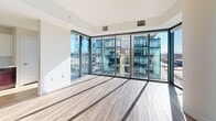Located at 100 Steele St in Denver's Cherry Creek neighborhood, this contemporary high-rise residence offers a thoughtfully designed single-floor layout with an abundance of natural light. Floor-to-ceiling windows frame sweeping panoramic views of the Denver skyline and the Rocky Mountains beyond, creating a dramatic and airy atmosphere throughout the living areas. Light wood-style flooring runs through the main living and kitchen spaces, complementing the clean, modern aesthetic.

The gourmet kitchen is a standout feature, equipped with stainless steel appliances including a gas range with a wall-mounted hood, a French door refrigerator, and a dishwasher. White subway tile backsplash, white quartz countertops, and a mix of white upper and dark espresso lower cabinetry provide a striking two-tone contrast. A kitchen island with sink adds both functionality and style.

The primary bathroom is elegantly appointed with a dual-sink vanity featuring dark cabinetry, pendant lighting, a glass-enclosed shower, and a soaking tub. A secondary bathroom offers a tub-shower combo with classic subway tile and a dark wood vanity. Bedrooms feature plush carpeting and generous closet space, including a spacious walk-in closet. A dedicated in-unit laundry area with full-size washer and dryer adds everyday convenience.