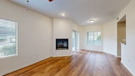 This single-floor residence offers a thoughtfully designed layout with a blend of warm materials and functional living spaces throughout. The open living area is a standout, showcasing rich hardwood flooring, crisp white walls, and a corner fireplace that serves as a focal point. Natural light pours in through a sliding glass door leading to a private balcony, as well as through a large window fitted with blinds. A ceiling fan adds comfort and visual appeal to the space.

The kitchen is well-equipped, featuring rich dark wood cabinetry, granite-style countertops, stainless steel appliances including an electric range, microwave, and refrigerator, along with a stainless steel sink. A raised breakfast bar provides a seamless connection to the adjacent living areas, while a tray ceiling adds architectural dimension overhead.

The bedroom is generously sized with plush carpeting, a ceiling fan, and a window with outdoor views. It connects directly to a walk-in closet and a bathroom vanity area with dark wood cabinetry and granite-style countertops. An additional carpeted room with a ceiling fan and sliding glass door offers flexible use as a second bedroom or sitting room. A dedicated laundry area with a full-size washer and dryer completes this comfortable and practical home.