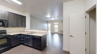 Located at 3033 W 71st Ave in Westminster, CO, this two-bedroom, one-bathroom residence offers a well-organized single-floor layout designed for comfortable everyday living. The open-concept design connects the kitchen and living room, creating a cohesive and functional common area. The kitchen is equipped with dark espresso cabinetry extending to the upper walls, a full suite of black appliances including a refrigerator, electric range, built-in microwave, and dishwasher, along with light-toned countertops and a peninsula that serves as both a workspace and a divider between the kitchen and living area. The living room is bright and open, featuring hardwood-style flooring, neutral-toned walls, and a glass-paneled exterior door with a transom window that invites natural light. Both bedrooms continue the hardwood-style flooring and are finished with neutral walls, ceiling fans, and windows that provide outside views. The primary bedroom includes a closet, while the second bedroom also benefits from natural light. The bathroom is clean and functional, featuring a full tub-shower combination, a dark-cabineted vanity with a light countertop, and a large mirror. Consistent finishes and a neutral color palette throughout give the space a cohesive, modern feel.