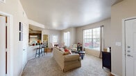 Located at 2100 Spencer Rd in Denton, TX, this single-story, 3-bedroom, 2-bathroom home offers a comfortable and well-organized layout. The inviting living room serves as the heart of the home, featuring plush carpeting, neutral walls, and multiple large windows dressed with blinds and sheer curtains that flood the space with natural light. A hardwood-floored entryway provides a clean transition into the carpeted living area.

The kitchen is equipped with rich dark wood cabinetry, light stone-finish countertops, a breakfast bar with seating, and hardwood flooring. White appliances and ample cabinet storage make this a fully functional space that flows conveniently into the dining area.

The primary bedroom features vaulted ceilings with a ceiling fan, soft carpet, and direct views into adjacent rooms. Each of the three bedrooms includes its own closet, offering generous storage. Secondary bedrooms are carpeted and well-lit with large windows providing outdoor views.

The bathrooms are finished with warm hardwood flooring, dark wood vanities, stone-finish countertops, and tub-shower combinations. Decorative shelving adds a thoughtful design touch. Throughout the home, a consistent neutral color palette and textured ceilings contribute to a warm, cohesive ambiance suited for everyday living.
