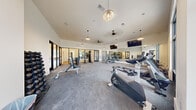 Located at 280 Salmon Brook St in Granby, CT, this well-appointed fitness center offers a comprehensive workout facility across a single floor. The space is organized into two distinct areas: a generously sized main gym floor and a separate multipurpose studio room.

The main workout area features vaulted ceilings that lend an open, airy feel to the space. Durable rubber-backed carpet flooring covers the gym floor, providing both comfort and functionality underfoot. The room is illuminated by a combination of stylish pendant lights and ceiling fans, ensuring adequate airflow and visibility throughout. Large windows along the walls allow natural light to fill the space while offering views to the outdoors. Full-length wall mirrors visually expand the room while serving as a practical training aid. Equipment includes a row of treadmills, ellipticals, stationary bikes, cable machines, a weight bench, and a dumbbell rack. Wall-mounted flat-screen televisions are positioned for easy viewing during workouts.

The secondary studio room is a clean, minimalist space featuring warm hardwood flooring and large wall mirrors, making it ideal for yoga, stretching, or group fitness activities. The crisp white walls and simple design keep the room bright and versatile. Glass-paneled doors connect the two areas, maintaining a sense of openness throughout the facility.