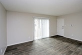 This single-floor unit offers a thoughtfully designed layout that maximizes functionality and comfort. The open-concept living and dining area is finished with durable wood-look flooring in a warm gray tone, neutral painted walls, and a textured ceiling. A large sliding glass door fitted with vertical blinds allows generous natural light to fill the space while providing direct outdoor access and pleasant exterior views.

The kitchen is a standout feature, showcasing rich, dark espresso cabinetry with modern hardware, granite-look countertops, and a classic white subway tile backsplash. Stainless steel appliances, including a refrigerator and dishwasher, complement the double-basin sink, making this kitchen as practical as it is visually appealing. A pendant light overhead adds a finishing touch to the space.

The bathroom is clean and efficiently laid out, featuring a full-size soaking tub and shower combination with crisp white surround walls. The straightforward, minimalist design keeps the space feeling fresh and easy to maintain.

Throughout the unit, consistent wood-look flooring ties the rooms together, while ample closet storage and a practical corridor connecting the key spaces add to the overall livability. This unit presents a modern, move-in-ready living environment with updated finishes throughout.