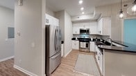 Located at 4209 E Beltline Ave NE in Grand Rapids, Michigan, this single-floor unit presents a clean, contemporary design with consistent finishes throughout. The kitchen is a standout feature, outfitted with white shaker-style cabinetry, dark granite countertops, stainless steel appliances including a gas range, built-in microwave, and French door refrigerator, and light wood-look flooring that adds warmth to the space. Recessed lighting and ample cabinetry provide both functionality and a polished aesthetic.

The living and dining areas continue the wood-look flooring, with the dining space anchored by a modern drum chandelier and neutral gray walls that create a calm, versatile backdrop. Multiple bedrooms feature plush wall-to-wall carpeting, large windows with outdoor views, and soft neutral tones, offering comfortable, light-filled retreats.

The bathrooms are finished with the same white shaker cabinetry and dark granite countertops found in the kitchen, maintaining design continuity. One bathroom includes a walk-in shower with glass enclosure, a wide vanity mirror with contemporary lighting, and wood-look flooring. Natural light flows throughout via windows dressed with clean white blinds, contributing to the bright and cohesive ambiance of the entire space.