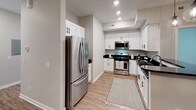 Located at 4209 E Beltline Ave NE in Grand Rapids, Michigan, this single-floor unit presents a clean, contemporary design with consistent finishes throughout. The kitchen is a standout feature, outfitted with white shaker-style cabinetry, dark granite countertops, stainless steel appliances including a gas range, built-in microwave, and French door refrigerator, and light wood-look flooring that adds warmth to the space. Recessed lighting and ample cabinetry provide both functionality and a polished aesthetic.

The living and dining areas continue the wood-look flooring, with the dining space anchored by a modern drum chandelier and neutral gray walls that create a calm, versatile backdrop. Multiple bedrooms feature plush wall-to-wall carpeting, large windows with outdoor views, and soft neutral tones, offering comfortable, light-filled retreats.

The bathrooms are finished with the same white shaker cabinetry and dark granite countertops found in the kitchen, maintaining design continuity. One bathroom includes a walk-in shower with glass enclosure, a wide vanity mirror with contemporary lighting, and wood-look flooring. Natural light flows throughout via windows dressed with clean white blinds, contributing to the bright and cohesive ambiance of the entire space.