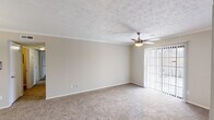 Located at 7028 Watchman Cir in Montgomery, Alabama, this single-story home offers a well-organized layout with a neutral color palette and consistent finishes throughout. The living room is generously proportioned, featuring plush carpeting, crown molding, a textured ceiling, and a ceiling fan with integrated lighting. Vertical blinds frame a sliding glass door that opens to the outdoors, allowing natural light to fill the space.

Adjacent to the living room, a dining area is defined by chair rail molding and a pendant light fixture overhead, creating a distinct yet open transition between entertaining spaces. A passthrough connects to the galley-style kitchen, which features white upper cabinetry, gray lower cabinetry, light countertops, a stainless steel refrigerator, and wood-look flooring that adds warmth and easy maintenance.

The bedrooms are carpeted and finished with textured ceilings. One bedroom includes a large window for natural light and a double sliding-door closet providing generous storage. Both bathrooms are updated with gray vanity cabinetry, light countertops, large mirrors, and wood-look flooring. One bathroom includes a shower-tub combination, while the other features a single vanity with brushed nickel hardware.
