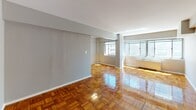Located on the fifth floor at 510 21st St NW in Washington, DC, this apartment offers a well-designed single-level layout with consistent, warm-toned parquet hardwood flooring throughout the main living areas and bedrooms. The expansive living room is a standout feature, bathed in natural light through a bank of large windows that frame urban cityscape views. The open flow between the living and dining areas creates a generous, airy feel. The kitchen has been thoughtfully updated with white shaker cabinetry, granite countertops, a classic subway tile backsplash, and a full suite of stainless steel appliances including a gas range, microwave, and refrigerator, complemented by wood-look flooring. The bedrooms continue the parquet hardwood theme and are well-proportioned, with one featuring a closet with bifold doors, a ceiling fan light fixture, and direct access to a private bathroom. The bathroom showcases a classic black-and-white tile design with white subway tile wainscoting accented by a bold black tile border. Throughout the unit, neutral gray walls provide a clean, versatile backdrop, and the overall ambiance is bright, functional, and move-in ready in a prime Washington, DC location.