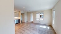 North Grove A1D, Unit 21-202, is a thoughtfully designed 710-square-foot, one-bedroom, one-bathroom apartment located in Riverside, CA 92501. The single-floor layout includes a kitchen, bedroom, hallway, bathroom, and a dedicated closet, maximizing functionality within a modern framework. The open living area features light-toned hardwood-style flooring and multiple large windows that flood the space with abundant natural light, offering views of the contemporary exterior building and surrounding landscaping. The kitchen is appointed with full stainless steel appliances, including a French-door refrigerator, range, microwave, and dishwasher, complemented by two-tone cabinetry, a marble-style subway tile backsplash, and recessed lighting. The 120-square-foot bedroom features plush carpeting and a large window with exterior views, providing a bright and comfortable retreat. A spacious walk-in closet with wire shelving offers ample storage. The bathroom includes a wood-toned vanity with an undermount sink, a white countertop, a large mirror, and a full shower-tub combo, all finished with light hardwood-style flooring. The building's modern stucco exterior features balconies with glass railings.