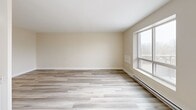 Located at 56 Main St N in Markham, Ontario, this well-appointed one-bedroom, one-bathroom unit offers a thoughtfully designed layout with modern finishes throughout. Light grey laminate flooring runs continuously across the entire space, complemented by crisp white trim and warm neutral walls that create a clean, cohesive aesthetic.

The open-concept living, dining, and kitchen area forms the heart of the unit. The kitchen is outfitted with white shaker-style cabinetry, granite-look countertops, a stainless steel double sink, and white appliances including a refrigerator and electric range. Generous counter space and ample upper and lower cabinetry provide excellent storage and functionality. The living and dining area benefits from multiple windows that bring in natural light and offer views of the surrounding greenery, with a glass door leading out to a private balcony.

The bedroom is a comfortable size, featuring a sliding-door closet, a window with outdoor views, and baseboard heating. The full bathroom includes a vanity with under-sink storage, a mirrored medicine cabinet, and a clean, all-white finish. Throughout the unit, flush-mount light fixtures provide consistent illumination, and the overall design emphasizes practicality and a bright, modern feel.