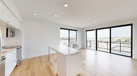 Located at 747 Hampden Ave in Saint Paul, MN, this modern 2-bedroom, 2-bathroom residence offers a thoughtfully designed single-floor layout with clean contemporary finishes throughout. The open-concept kitchen and living area serves as the heart of the home, anchored by a sleek white kitchen island with ample counter space. The kitchen is outfitted with stainless steel appliances — including a refrigerator, range, microwave, and dishwasher — paired with white cabinetry, a tiled backsplash, and light hardwood flooring that extends seamlessly into the living area. Large floor-to-ceiling windows and a sliding glass door to a private balcony flood the space with natural light and offer open views of the surrounding Saint Paul neighborhood. Both bedrooms feature plush carpeting and crisp white walls, providing a calm retreat. The two bathrooms are finished in a clean, minimalist style — one with a soaking tub and shower combination, and the other with a glass-enclosed walk-in shower — each featuring white floating vanities, under-mount sinks, and hardwood-style flooring. A hallway houses an in-unit washer, adding everyday convenience. Recessed lighting throughout enhances the bright, modern ambiance of this well-appointed residence.