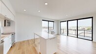 Located at 747 Hampden Ave in Saint Paul, MN, this modern 2-bedroom, 2-bathroom residence offers a thoughtfully designed single-floor layout with clean contemporary finishes throughout. The open-concept kitchen and living area serves as the heart of the home, anchored by a sleek white kitchen island with ample counter space. The kitchen is outfitted with stainless steel appliances — including a refrigerator, range, microwave, and dishwasher — paired with white cabinetry, a tiled backsplash, and light hardwood flooring that extends seamlessly into the living area. Large floor-to-ceiling windows and a sliding glass door to a private balcony flood the space with natural light and offer open views of the surrounding Saint Paul neighborhood. Both bedrooms feature plush carpeting and crisp white walls, providing a calm retreat. The two bathrooms are finished in a clean, minimalist style — one with a soaking tub and shower combination, and the other with a glass-enclosed walk-in shower — each featuring white floating vanities, under-mount sinks, and hardwood-style flooring. A hallway houses an in-unit washer, adding everyday convenience. Recessed lighting throughout enhances the bright, modern ambiance of this well-appointed residence.