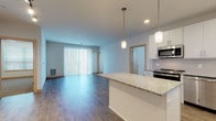 Located at 3601 Cross Hill Dr in Madison, Wisconsin, this single-floor residence offers a well-designed, open-concept layout with modern finishes throughout. The kitchen is a standout feature, showcasing crisp white cabinetry, a subway tile backsplash, stainless steel appliances including a refrigerator, range, and microwave, and a granite-topped peninsula with stylish pendant lighting overhead. Wood-look flooring flows seamlessly through the kitchen and living area, which is bathed in natural light from large sliding glass doors fitted with vertical blinds. The spacious living area provides an open and airy feel, ideal for both everyday living and entertaining. The bedroom features plush carpet, a ceiling fan, and a bright window with blinds, creating a comfortable and restful retreat. A generously sized walk-in closet with wire shelving offers ample storage. Two bathrooms serve the unit — one featuring a tub-shower combination and a granite vanity, and a second with a sliding glass shower enclosure, a matching granite vanity, and convenient access to an additional linen closet. Throughout the unit, light wood trim, recessed lighting, and a neutral color palette contribute to a clean, contemporary aesthetic.