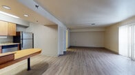 Located at 7275 N Port Washington Rd in Glendale, Wisconsin, this single-floor space offers a functional and well-appointed layout designed for comfortable everyday living. The open-plan main living area is expansive and airy, featuring light-toned wood-look flooring that runs seamlessly throughout the unit, neutral warm-beige walls, and ample overhead lighting. Large vertical blinds allow for natural light to filter in, enhancing the bright and welcoming ambiance of the space. A fireplace adds a focal point to the living area, complementing the clean, understated design.

The kitchen is efficiently designed with warm honey-toned wood cabinetry, granite countertops, a tile backsplash, and a full suite of stainless steel appliances, including a refrigerator, range, microwave, and dishwasher. A built-in breakfast bar with seating provides a casual dining option directly adjacent to the kitchen.

The bathroom features an extended granite-topped vanity with warm wood cabinetry, a large illuminated mirror, and a full-length mirror, creating a bright and practical grooming space. The entryway offers a welcoming transition into the main living areas, completing this thoughtfully designed, move-in-ready space in the heart of Glendale.