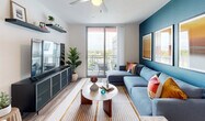 Located in Homestead, FL, this thoughtfully designed 3-bedroom, 2-bathroom residence offers a modern aesthetic with functional living spaces throughout its single-floor layout. The living room makes a bold statement with a deep teal accent wall, wide-plank wood-style flooring, a ceiling fan, and a glass sliding door that opens to a private balcony with open views of the surrounding area, filling the space with natural light. The kitchen is outfitted with sleek white cabinetry extending to the ceiling, stainless steel appliances including a range, built-in microwave, and full-size refrigerator, plus a undermount sink and clean white countertops. The primary bedroom features a dedicated walk-in closet, a ceiling fan, and a soft gray accent wall, while additional bedrooms offer bright windows with outdoor views and wood-style flooring. Both bathrooms are finished in a clean, contemporary style — one featuring a frameless glass walk-in shower, and the other a full tub-shower combination with a backlit vanity mirror. A dedicated closet provides additional storage. Throughout the residence, consistent wood-style flooring, neutral tones, and natural light create a cohesive, modern ambiance.