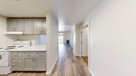 This well-appointed one-bedroom, one-bathroom residence in Everett, WA offers a thoughtfully designed layout across a single level. The welcoming entrance leads down a clean hallway into the open living area, where wood-style plank flooring flows throughout. The living room is a standout space, featuring elevated ceilings, a corner fireplace with a clean white surround, and a sliding glass door topped with a transom window that opens to a private balcony, filling the room with natural light and outdoor views. A ceiling fan adds both function and style to the space.

The kitchen is efficiently designed with gray shaker-style cabinetry, stone-look countertops, and a pass-through opening that connects it to the living area, creating an open and airy feel. The bedroom offers a generous footprint with soft wall-to-wall carpeting, a natural window view, and a dedicated closet for ample storage.

The bathroom is finished with a gray vanity, stone-look countertop, a large mirror, chrome fixtures, and a full tub-shower combination, maintaining the cohesive, updated aesthetic found throughout the home. Clean white walls, crisp trim, and consistent finishes tie the entire space together with a modern, neutral palette.