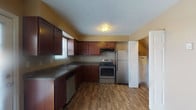 Located in Circleville, Ohio, this two-floor residential space offers a practical and comfortable layout across two levels. The main floor features a carpeted living area filled with natural light from a front-facing window, with a staircase providing access to the upper level. The kitchen is well-appointed with rich dark wood cabinetry, dark countertops, and wood-look flooring. It includes stainless steel appliances — an electric range, refrigerator, and dishwasher — along with a sink and ample cabinet storage. A door off the kitchen provides additional access, enhancing the flow of the space. A full bathroom is conveniently located on this level, featuring a tub-shower combination, a white vanity with storage, and wood-look flooring. The bedrooms are carpeted and finished in neutral warm tones, each with windows that bring in natural light. Baseboard heating is present throughout, and wall-mounted air conditioning units provide cooling in select rooms. One bedroom features a walk-in closet, adding useful storage. Textured ceilings appear in several rooms, contributing to the space's classic character. Overall, the layout is straightforward and functional, well-suited for everyday residential living.