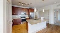 Located at 250 District Dr in Asheville, NC, this single-floor, three-bedroom, two-bathroom residence offers a well-designed layout across a generously sized floor plan. The open-concept kitchen and living area serves as the heart of the home, featuring rich dark-wood cabinetry, granite countertops, a center island with a undermount sink, stainless steel appliances, a subway tile backsplash, and track lighting accented by pendant lights — all set atop warm wood-style flooring. A dedicated pantry and in-unit laundry add to the home's practicality.

The three bedrooms are carpeted for comfort and include ceiling fans and windows that bring in natural light with views of the surrounding community. The spacious primary bedroom connects directly to an en-suite bathroom equipped with a dual-sink granite vanity, rich wood cabinetry, a glass-enclosed walk-in shower, and wood-style flooring. A walk-in closet with wire shelving provides ample storage. The second bathroom features a tiled tub-shower combination, a granite-topped vanity, and coordinating finishes. Throughout the home, seven closets ensure exceptional storage, and clean white walls with bright trim contribute to a fresh, modern aesthetic.