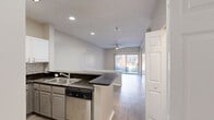 Located at Asbury Square in Dunwoody, Georgia, this two-bedroom, one-bathroom residence offers a well-organized single-level layout designed for comfortable everyday living. The open-concept kitchen and living area serves as the heart of the home, featuring light wood-look tile flooring, a peninsula with dark granite countertops, white upper cabinetry, gray lower cabinets, a classic subway tile backsplash, and a full suite of stainless steel appliances including a gas range, microwave, refrigerator, and dishwasher. The living room extends naturally from the kitchen and includes a ceiling fan and sliding glass door that opens to an outdoor area, allowing natural light to fill the space. Both bedrooms are carpeted and finished with neutral tones, offering a calm and functional environment. The primary bedroom provides a comfortable amount of floor space and connects conveniently to the shared bathroom. The second bedroom includes a walk-in closet and windows overlooking greenery, enhancing its sense of privacy. The bathroom is finished with wood-look tile flooring, a dark granite vanity top, and a large mirror. Two dedicated closets across the unit add practical storage throughout this thoughtfully laid-out Dunwoody residence.