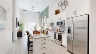 This thoughtfully designed one-bedroom, one-bathroom home in Allen, Texas offers an efficient yet refined living experience across a single floor. Soaring ceilings throughout the open-concept kitchen and living area create an impressive sense of volume and airiness, enhanced by large windows and a sliding glass door that flood the space with natural light and provide direct access to an outdoor area.

The kitchen is a standout feature, equipped with stainless steel appliances including a side-by-side refrigerator, range, and built-in microwave. Crisp white shaker cabinetry with matte black hardware, a grey subway tile backsplash, and a granite-topped island with bar seating make this kitchen as functional as it is attractive. A dedicated pantry adds valuable storage.

The living area flows seamlessly from the kitchen, anchored by the dramatic ceiling height and light-toned luxury vinyl plank flooring. The bedroom is a comfortable retreat with large windows that invite natural light. The full bathroom features a granite vanity, tile-surround soaking tub, and direct access to a well-organized walk-in closet. A dedicated in-unit laundry room with full-size washer and dryer completes this well-appointed home.