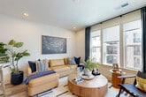 Located at 3310 S Tryon St in Charlotte, NC, this well-appointed one-bedroom, one-bathroom unit offers a thoughtfully designed layout across a single floor. Light-toned hardwood-style flooring runs through the main living areas, complementing the clean, neutral color palette throughout. A welcoming hallway leads into the open-concept kitchen and living room, where large windows flood the space with natural light. The kitchen features gray flat-front cabinetry, stainless steel appliances including a refrigerator, electric range, and built-in microwave, plus a white peninsula with bar seating illuminated by a sleek pendant light fixture. The living area offers generous proportions and direct access to a private balcony through a glass door. A separate den provides flexible additional living or workspace. The carpeted bedroom is comfortably sized, benefits from a ceiling fan, large window, and direct access to a walk-in closet. The full bathroom includes a tub-shower combination, wood-tone vanity with white countertop, and wood-look flooring. Two closets, a dedicated laundry area, and a utility room round out the practical offerings of this efficiently designed home.