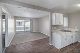 Located at 555 E Fruitvale Ave in Hemet, CA, this one-bedroom, two-bathroom unit offers a practical and efficiently laid-out single-floor living space. The living room is carpeted and finished with neutral beige tones, a textured ceiling, and a sliding glass door that opens to a private balcony with an iron railing, allowing natural light to flow in and providing outdoor views of the surrounding community. The entryway transitions between wood-look flooring and carpet, delineating the living and kitchen areas. The galley-style kitchen features white shaker cabinetry with brushed nickel hardware, light stone-look countertops, a stainless steel sink, wood-look flooring, and a white electric range with overhead ventilation. Two closets provide ample storage throughout the unit. The bedroom is a comfortable size, carpeted, and includes its own sliding glass door access to the balcony, enhancing ventilation and natural light. Both bathrooms include a tub and shower combination with clean white surrounds and chrome fixtures. The unit's consistent neutral color palette and textured ceilings give the space a cohesive, low-maintenance aesthetic throughout.