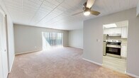 Located at 1515 Penn Avenue in Wilkinsburg, PA, this one-bedroom, one-bathroom unit offers a practical and well-appointed single-floor layout. The combined living and dining area is a comfortable, open space featuring warm neutral carpet, a tiled ceiling, and a ceiling fan with integrated lighting. Vertical blinds cover a sliding glass door that brings in natural light. The kitchen is notably updated, showcasing white shaker-style cabinetry, stone-look countertops, light wood-look vinyl flooring, and a full suite of stainless steel appliances including a refrigerator, electric range with overhead ventilation, and a sink with ample counter space. The spacious primary bedroom offers plush carpeting, a tiled ceiling, a louvered bifold closet door, and a window fitted with vertical blinds for light control. The bathroom is clean and functional, featuring a white vanity with storage, a tiled tub/shower combination, and light wood-look flooring. Neutral gray walls and white trim are consistent throughout, creating a cohesive, move-in-ready aesthetic across the entire unit.