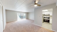 Located at 1515 Penn Avenue in Wilkinsburg, PA, this one-bedroom, one-bathroom unit offers a practical and well-appointed single-floor layout. The combined living and dining area is a comfortable, open space featuring warm neutral carpet, a tiled ceiling, and a ceiling fan with integrated lighting. Vertical blinds cover a sliding glass door that brings in natural light. The kitchen is notably updated, showcasing white shaker-style cabinetry, stone-look countertops, light wood-look vinyl flooring, and a full suite of stainless steel appliances including a refrigerator, electric range with overhead ventilation, and a sink with ample counter space. The spacious primary bedroom offers plush carpeting, a tiled ceiling, a louvered bifold closet door, and a window fitted with vertical blinds for light control. The bathroom is clean and functional, featuring a white vanity with storage, a tiled tub/shower combination, and light wood-look flooring. Neutral gray walls and white trim are consistent throughout, creating a cohesive, move-in-ready aesthetic across the entire unit.