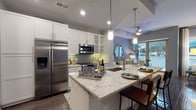 Located in the heart of Midtown Atlanta at 782 Peachtree St NE, this single-floor residence combines contemporary design with functional living. The open-concept kitchen is a standout feature, showcasing granite countertops, white shaker cabinetry with glass-front upper cabinets, a green subway tile backsplash, and a full suite of stainless steel appliances including a side-by-side refrigerator, range, and built-in microwave. A large kitchen island with an undermount sink provides additional prep space and seating, complemented by modern pendant lighting overhead. Rich dark hardwood flooring flows throughout the main living areas, anchoring the contemporary aesthetic. The living room is bright and inviting, with large sliding glass doors that open to a private outdoor patio, flooding the space with natural light and offering views of the surrounding greenery. The bedroom features a generous window with outdoor views, a tray ceiling detail, and plush carpeting for added comfort. The bathroom is thoughtfully designed with granite countertops, white cabinetry, large-format tile flooring, and a full tub-shower combination. A stacked in-unit washer and dryer adds everyday convenience. The overall ambiance is modern and cohesive, with neutral tones and quality finishes throughout.